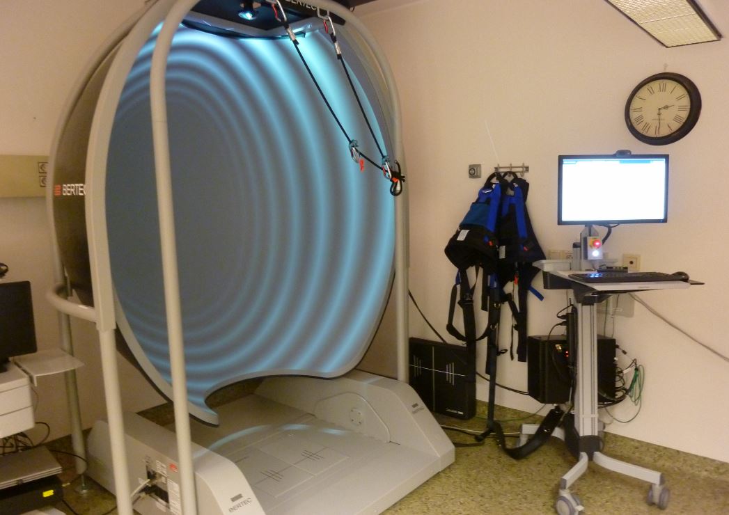 Balanseplattform og bord med pc, klokke på vegg, i undersøkelsesrom.