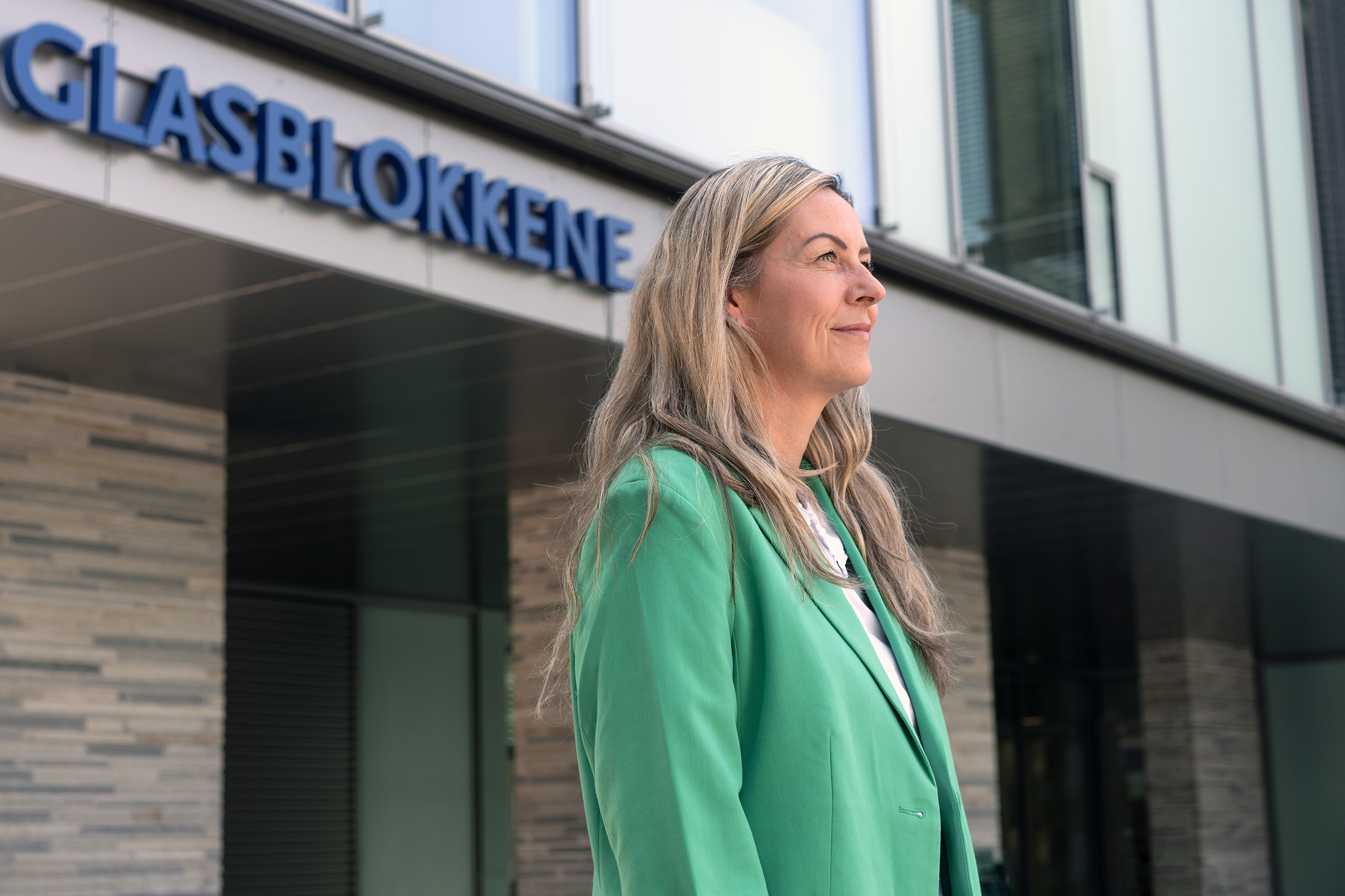 A person in a green jacket in front of a building