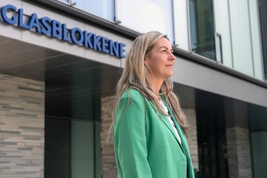 A person in a green jacket in front of a building