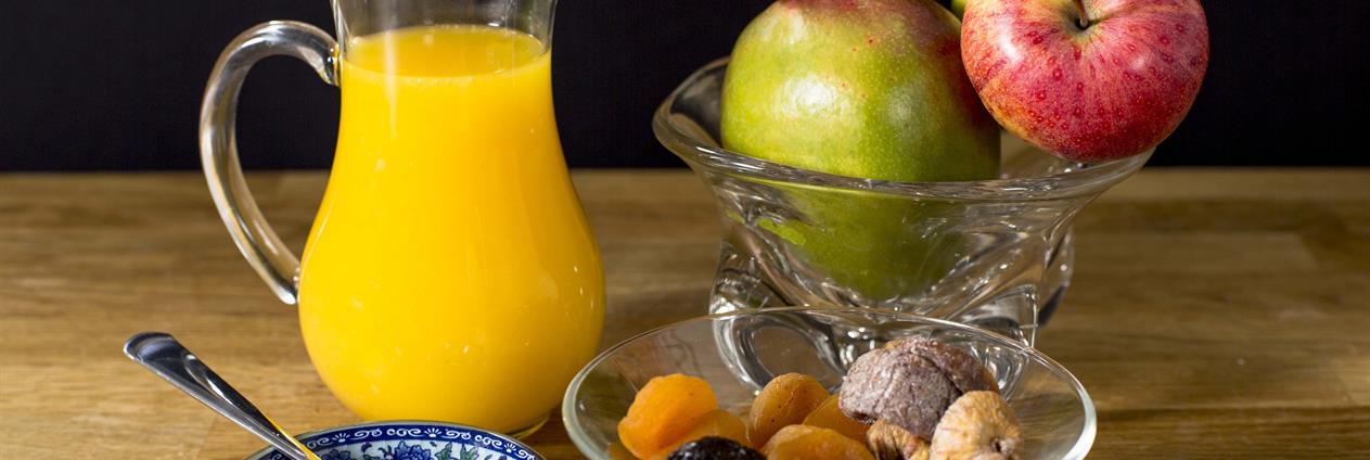 Et glass juice ved siden av en bolle med frukt