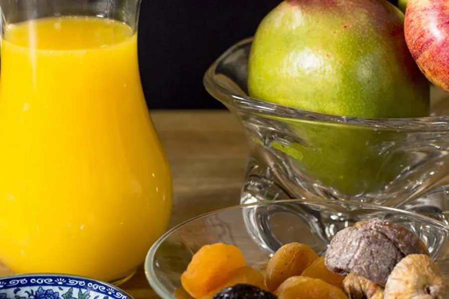 Et glass juice ved siden av en bolle med frukt