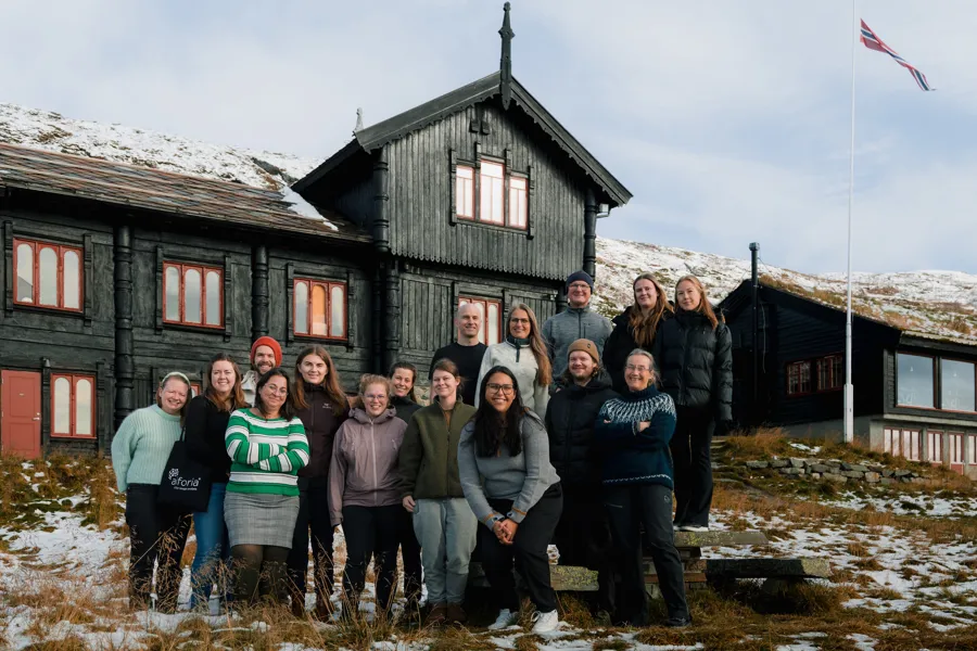 Gruppe av mennesker ute ved en gammel bygning på fjellet