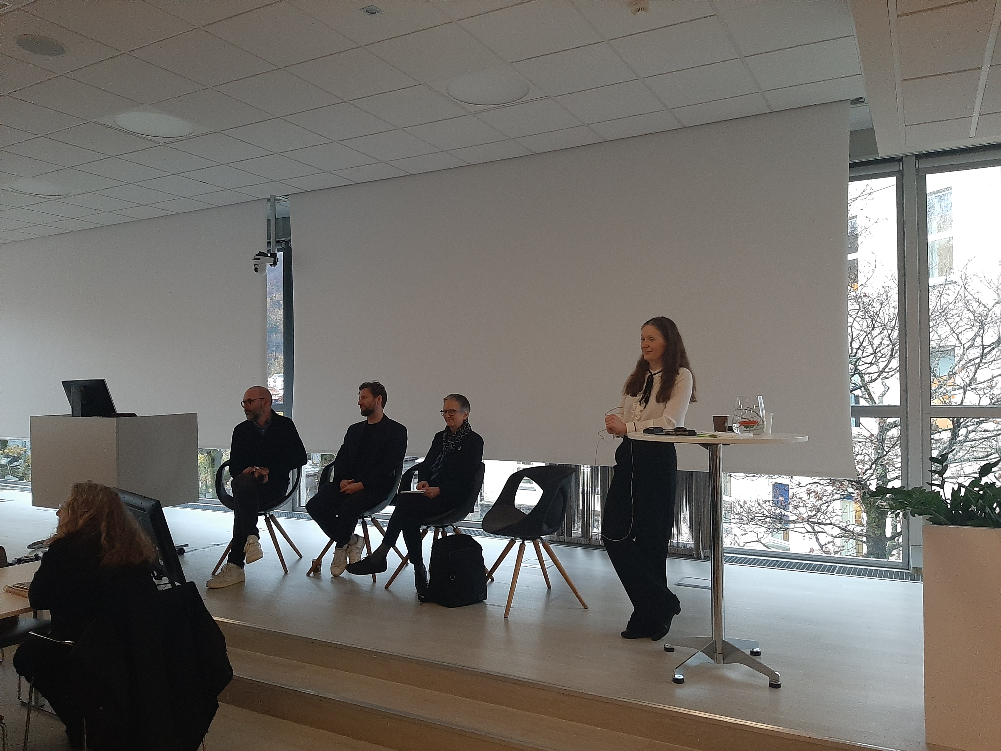 En person som står foran en gruppe mennesker som sitter ved et bord