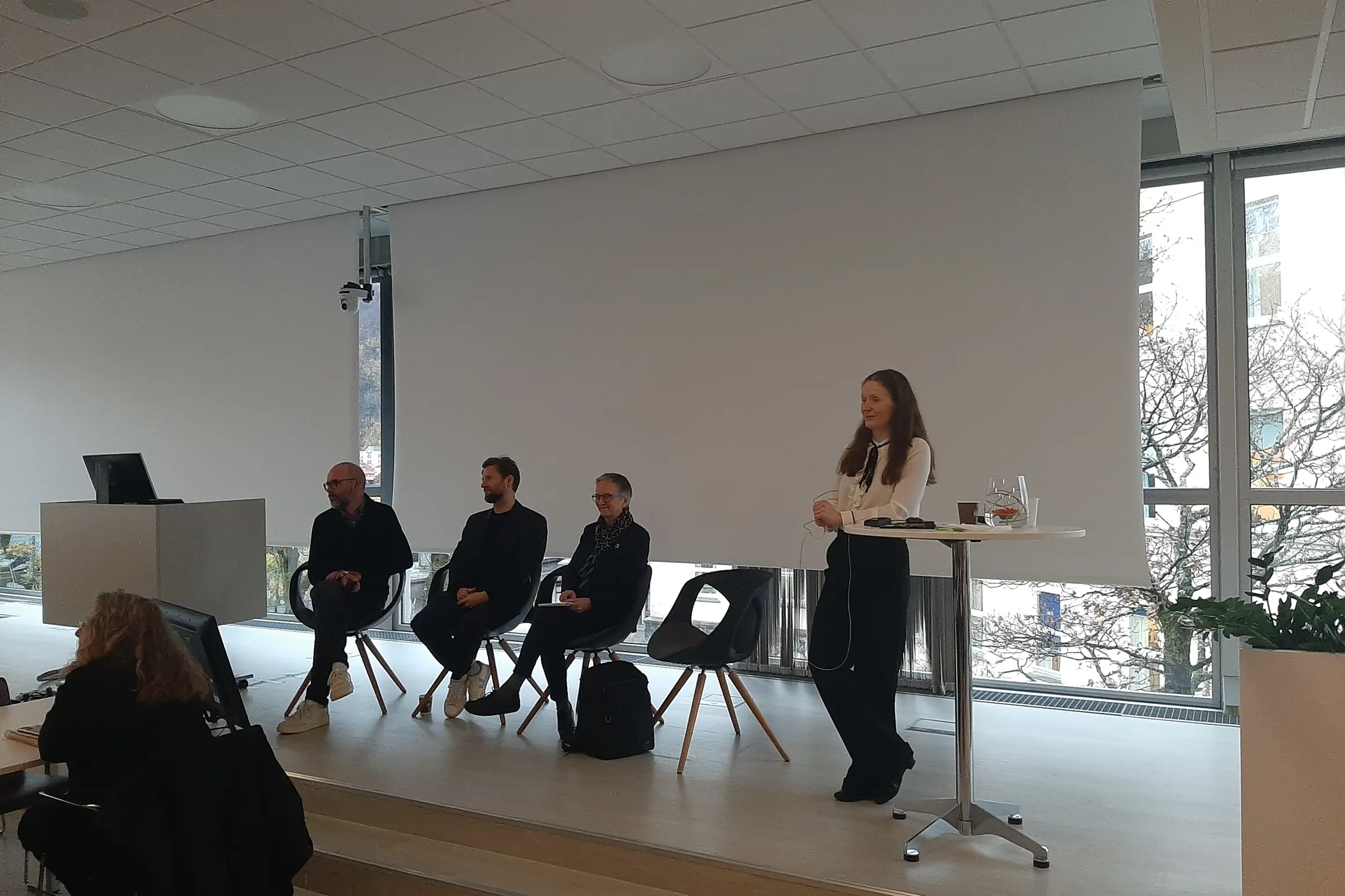 En person som står foran en gruppe mennesker som sitter ved et bord