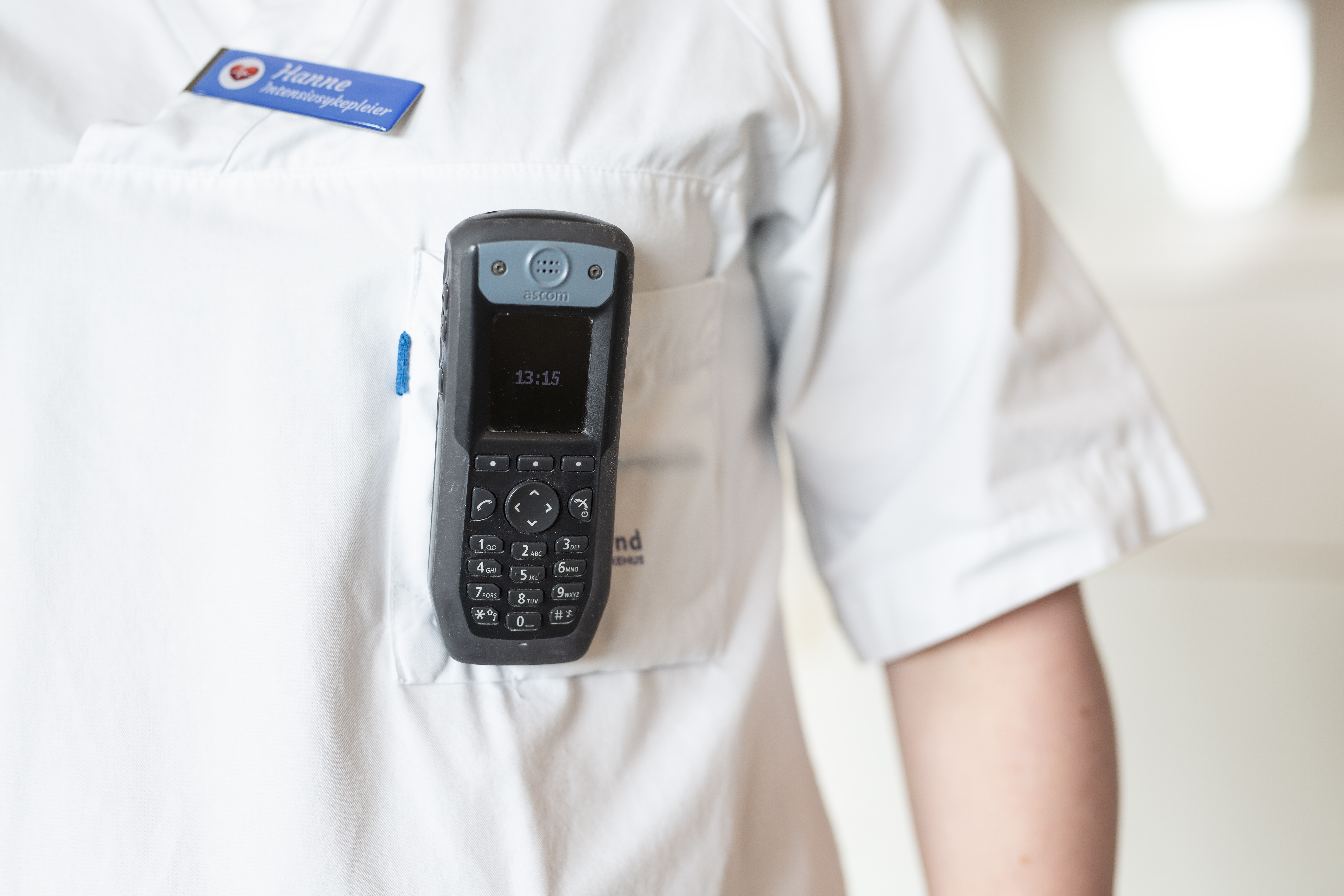 Foto av uniformert kvinne med telefon i brystlommen.