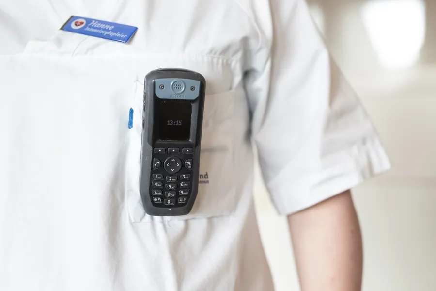 Foto av uniformert kvinne med telefon i brystlommen