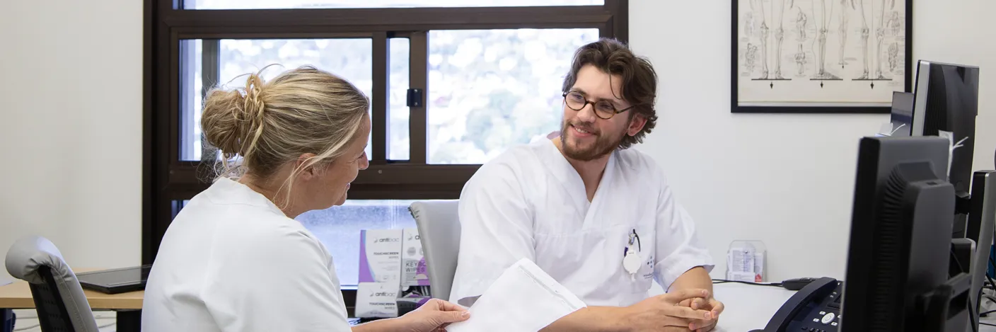 lege og sjukepleiar diskuterer pasient ved PC på eit vaktrom