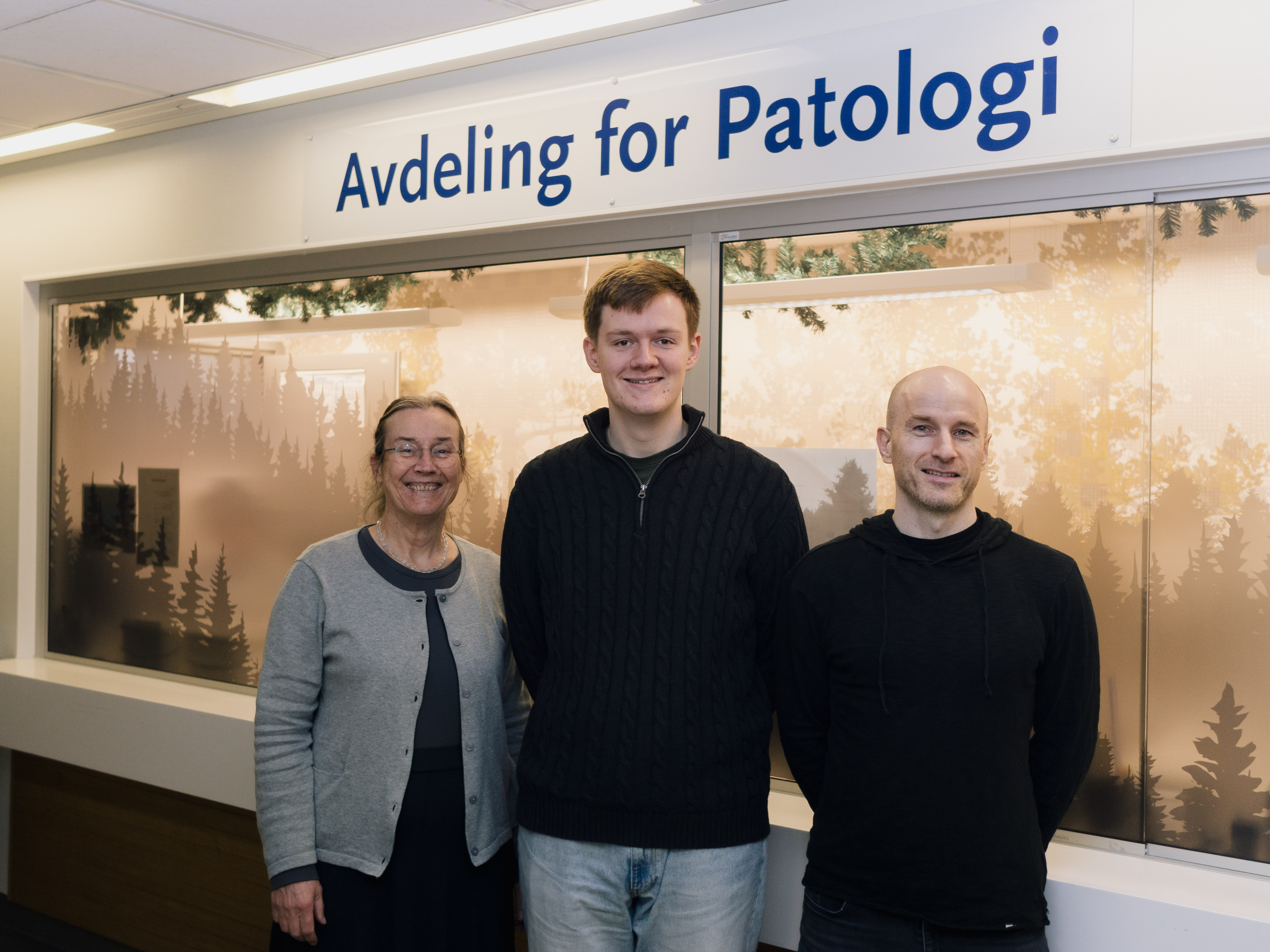 En gruppe menn som poserer for et bilde foran et skilt