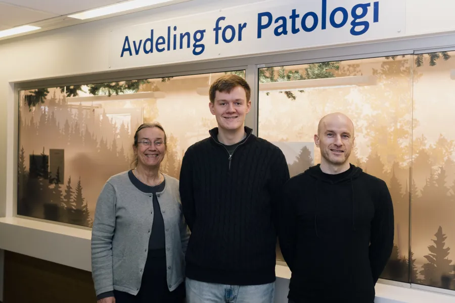 En gruppe menn som poserer for et bilde foran et skilt