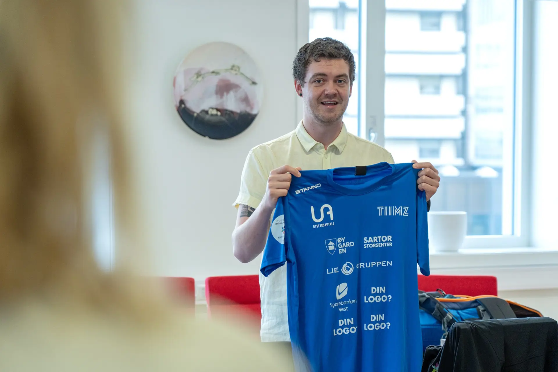 En mann som holder et blått og hvitt skilt foran et vindu