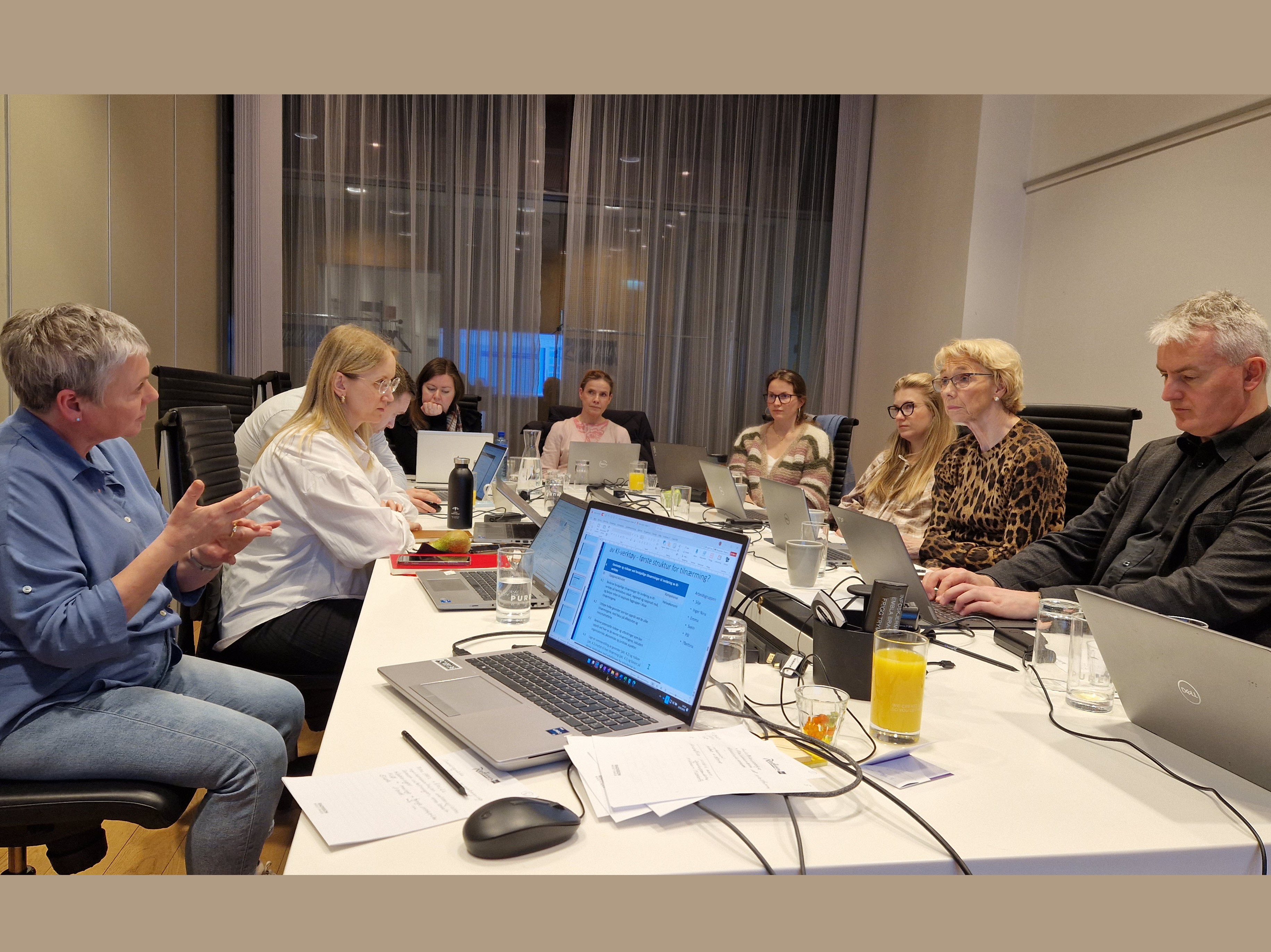 En gruppe mennesker som sitter rundt et bord med bærbare datamaskiner