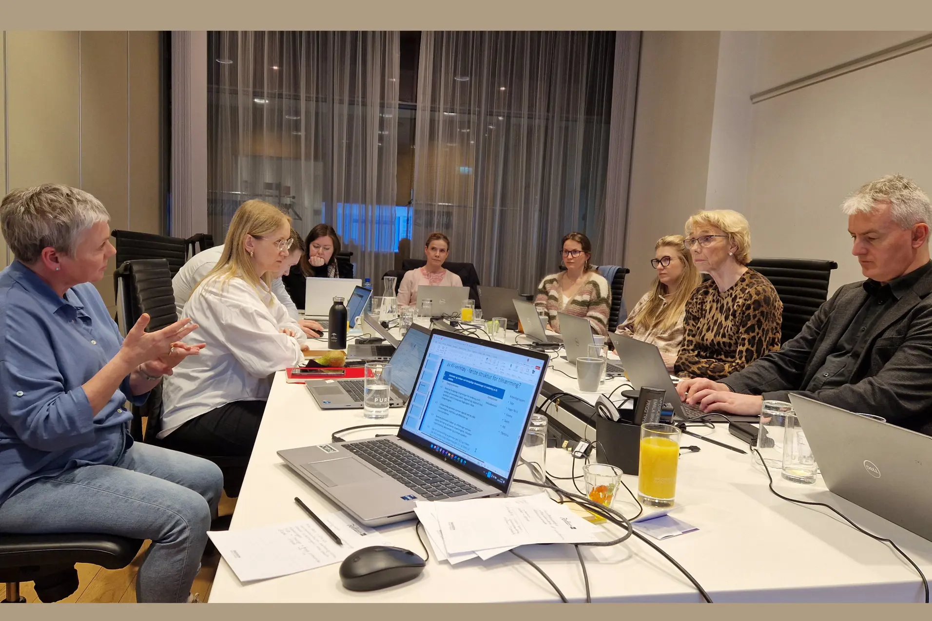 En gruppe mennesker som sitter rundt et bord med bærbare datamaskiner