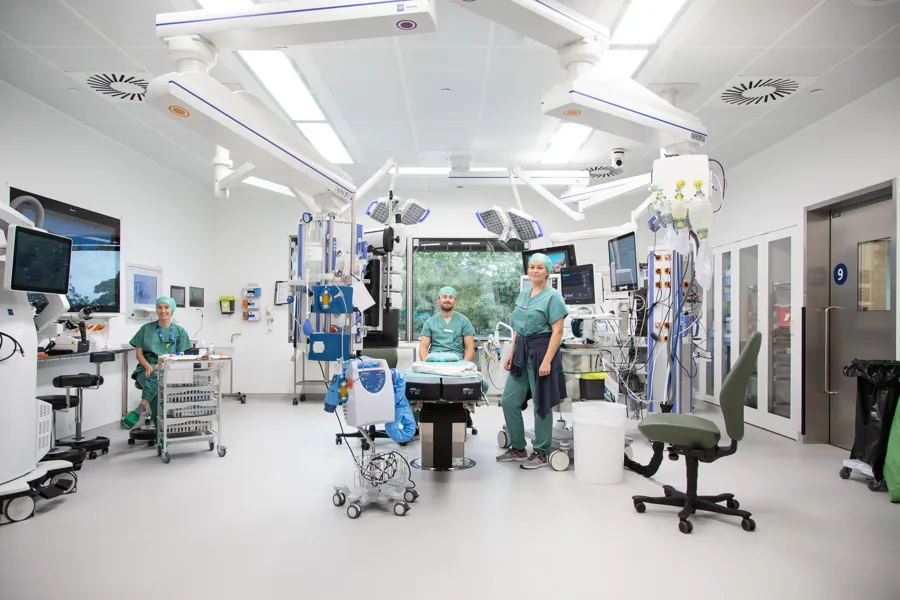 En operasjonssal med tre mennesker kledd i grønne uniformer