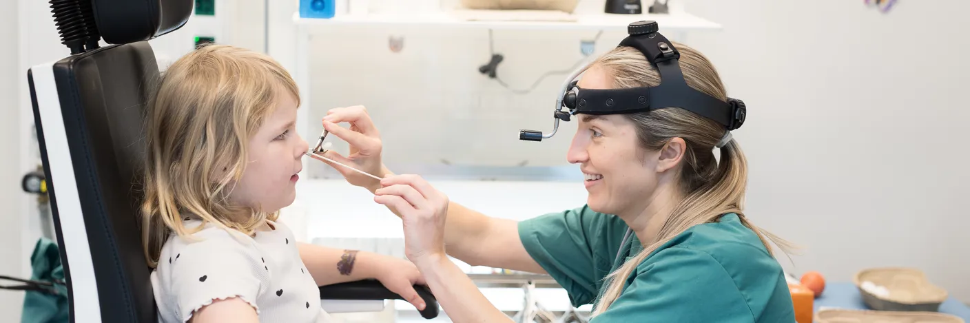 En jente blir undersøkt i nesen av en lege