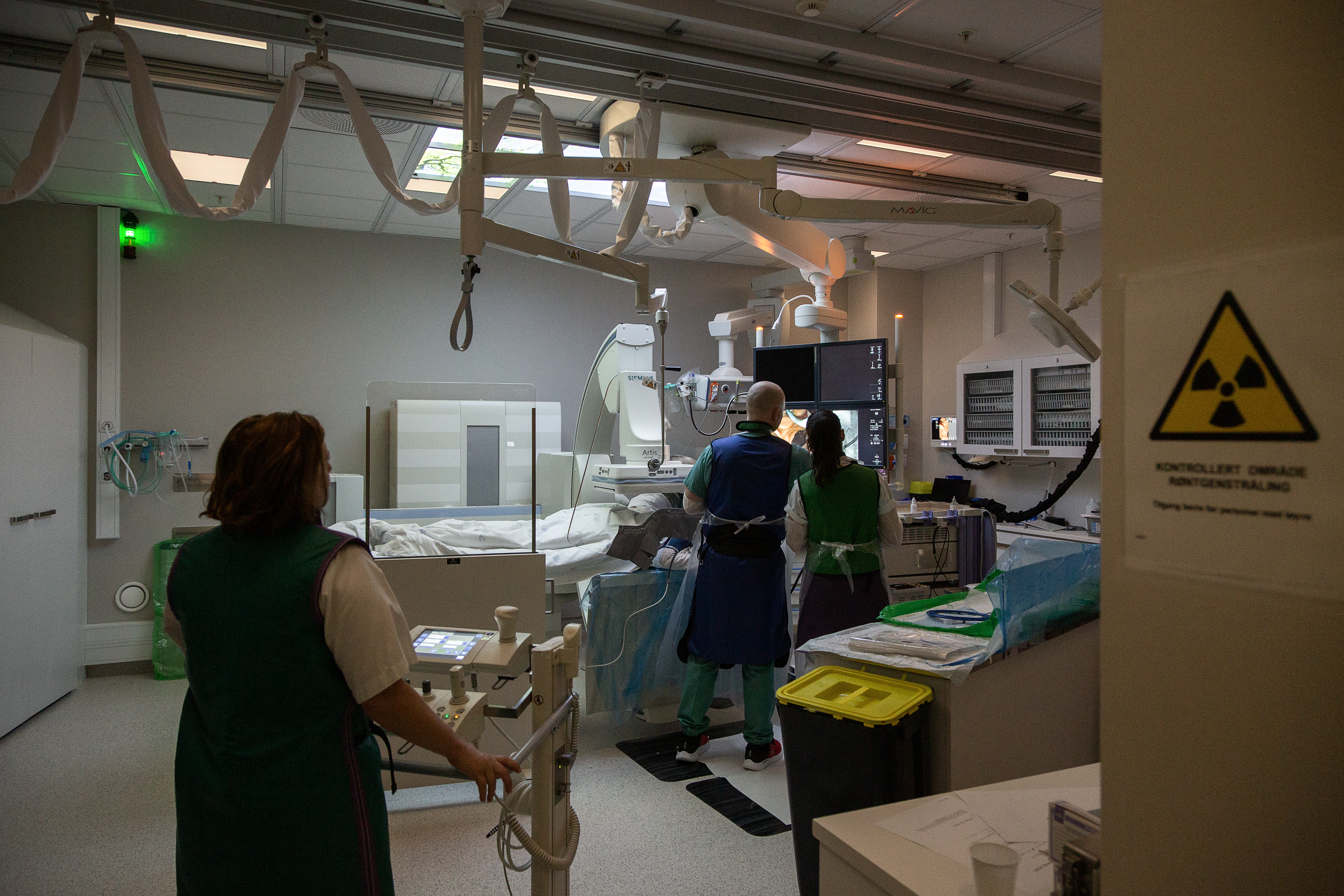 En pasient ligger på en undersøkelsesbenk med felre helsepersonell rundt, det utføres en skopiundersøkelse