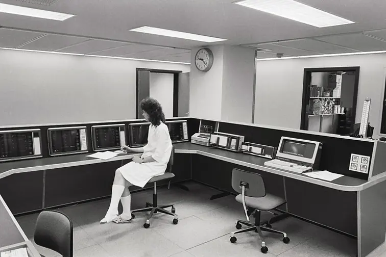 En person som sitter ved en sentral med flere datamaskiner