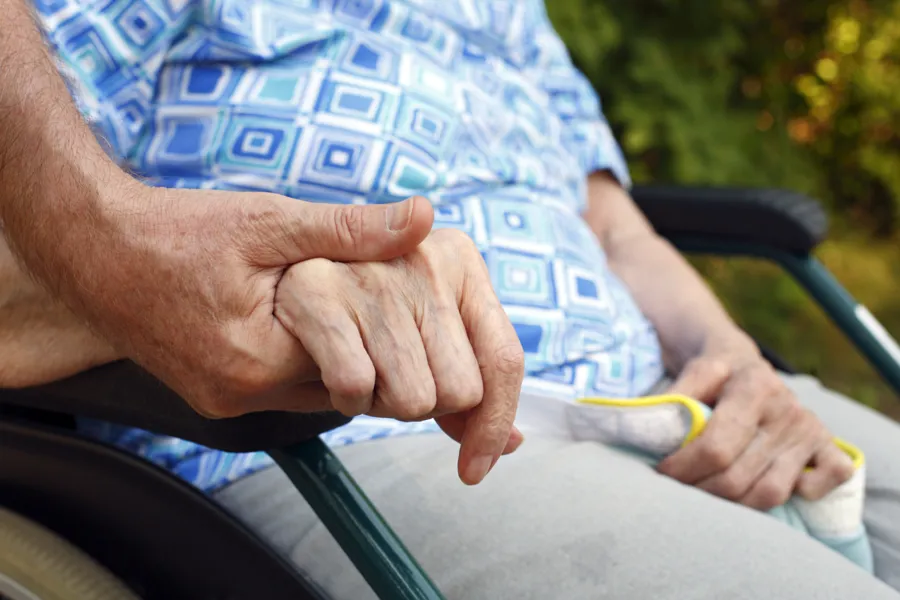 foto av person i rullestol som holdes i hånden.