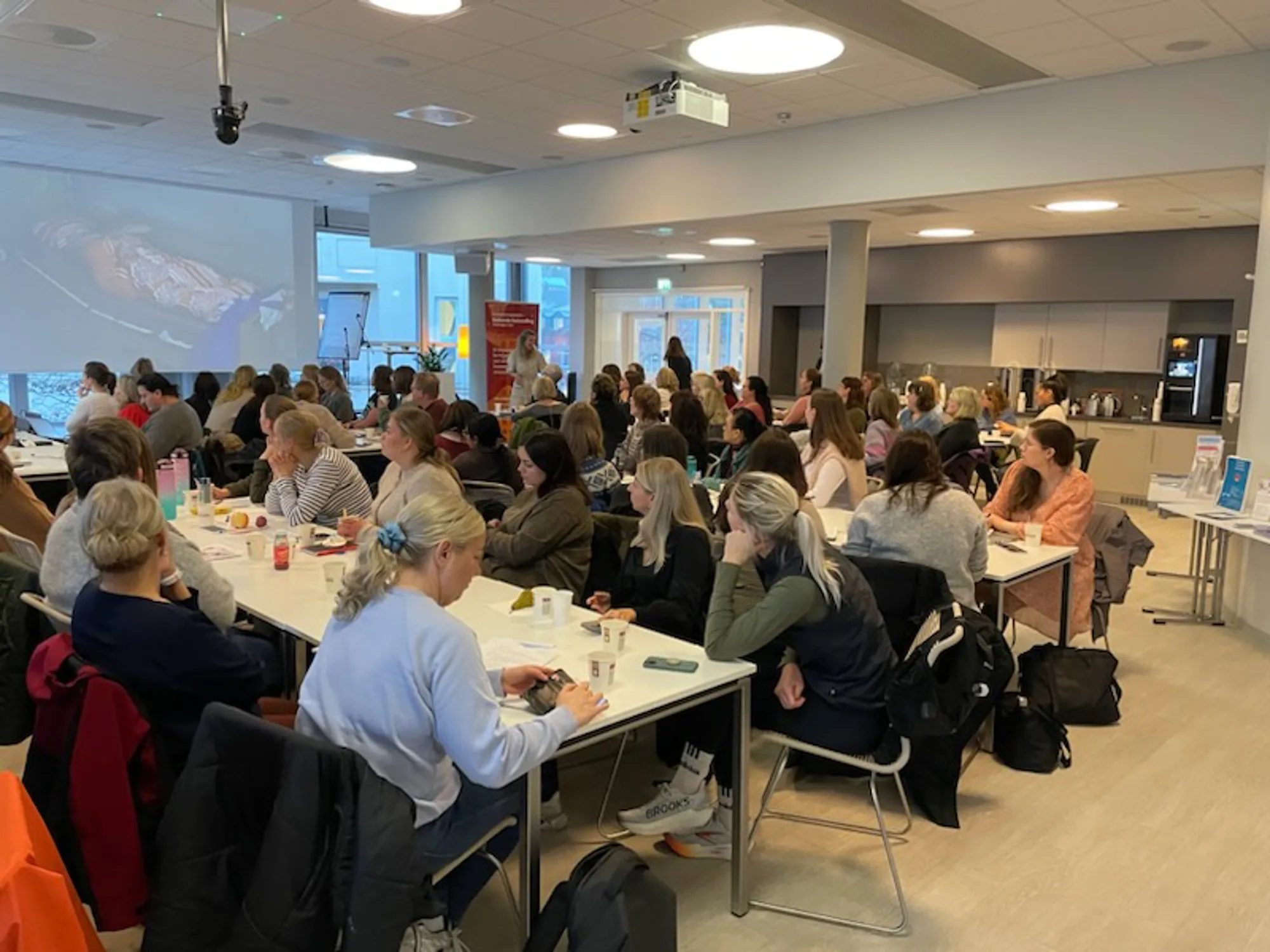 En gruppe mennesker som sitter ved bord i konferansesal