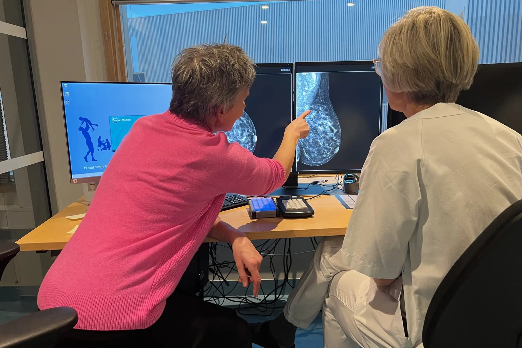 Et par personer som sitter ved et skrivebord og ser på en dataskjerm