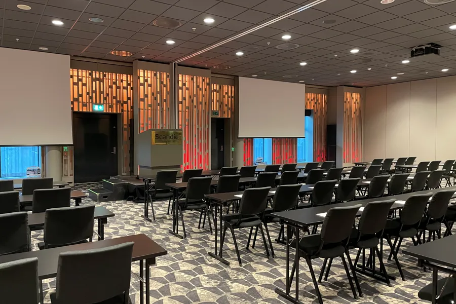 Et rom med stolrader og en skjerm på baksiden