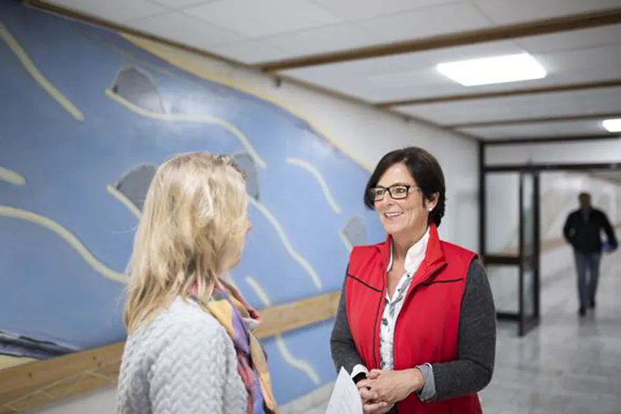 En person i rød vest snakker med en person