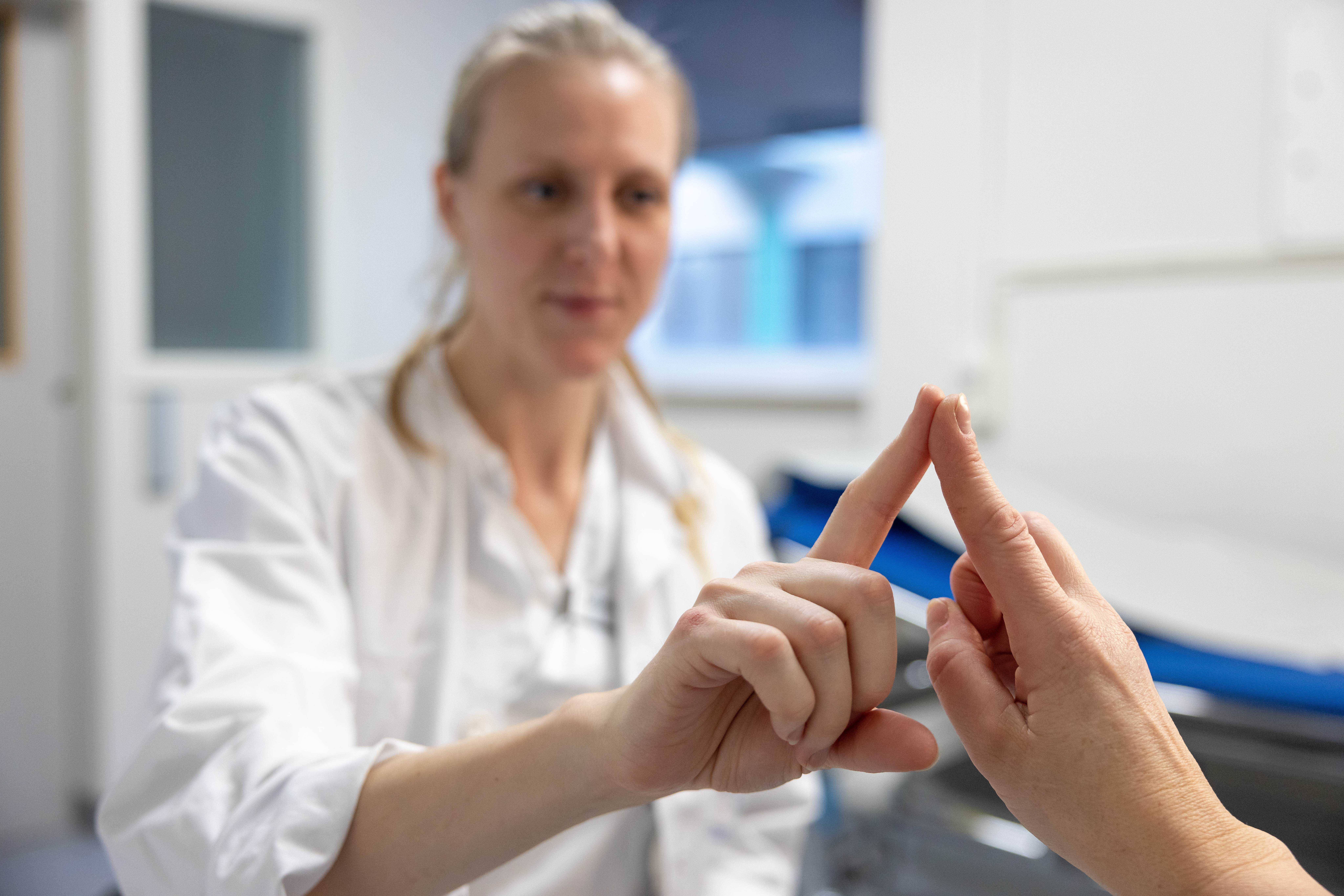 A clinical nurse testing a patient's coordination by having they pointing their finger against hers.