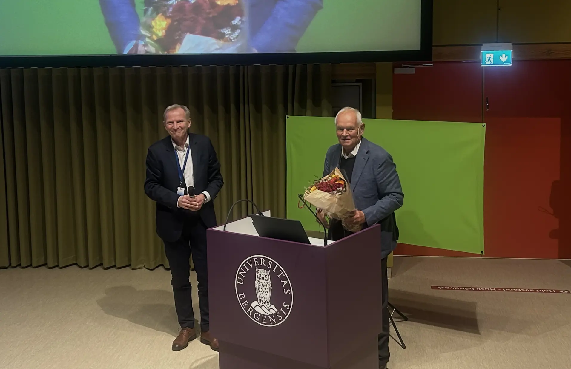 En person som står på et podium med en person som holder en blomsterbukett