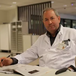 Lege i kvit frakk som sit