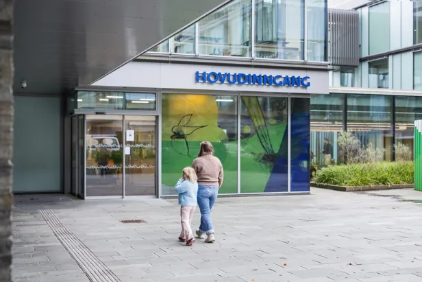 En voksen og et barn foran en bygning