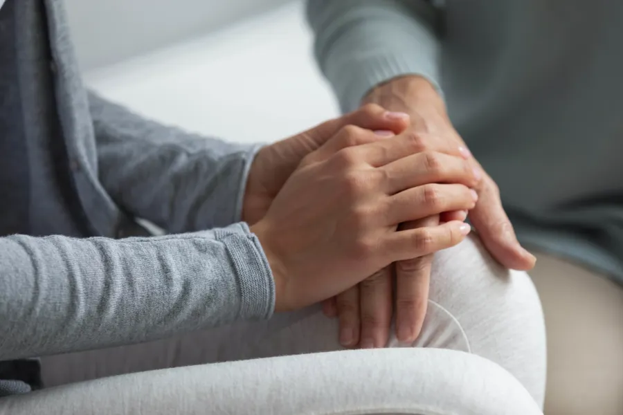 Nærbilde av hendene til to som holder hverandre i hendene. Foto