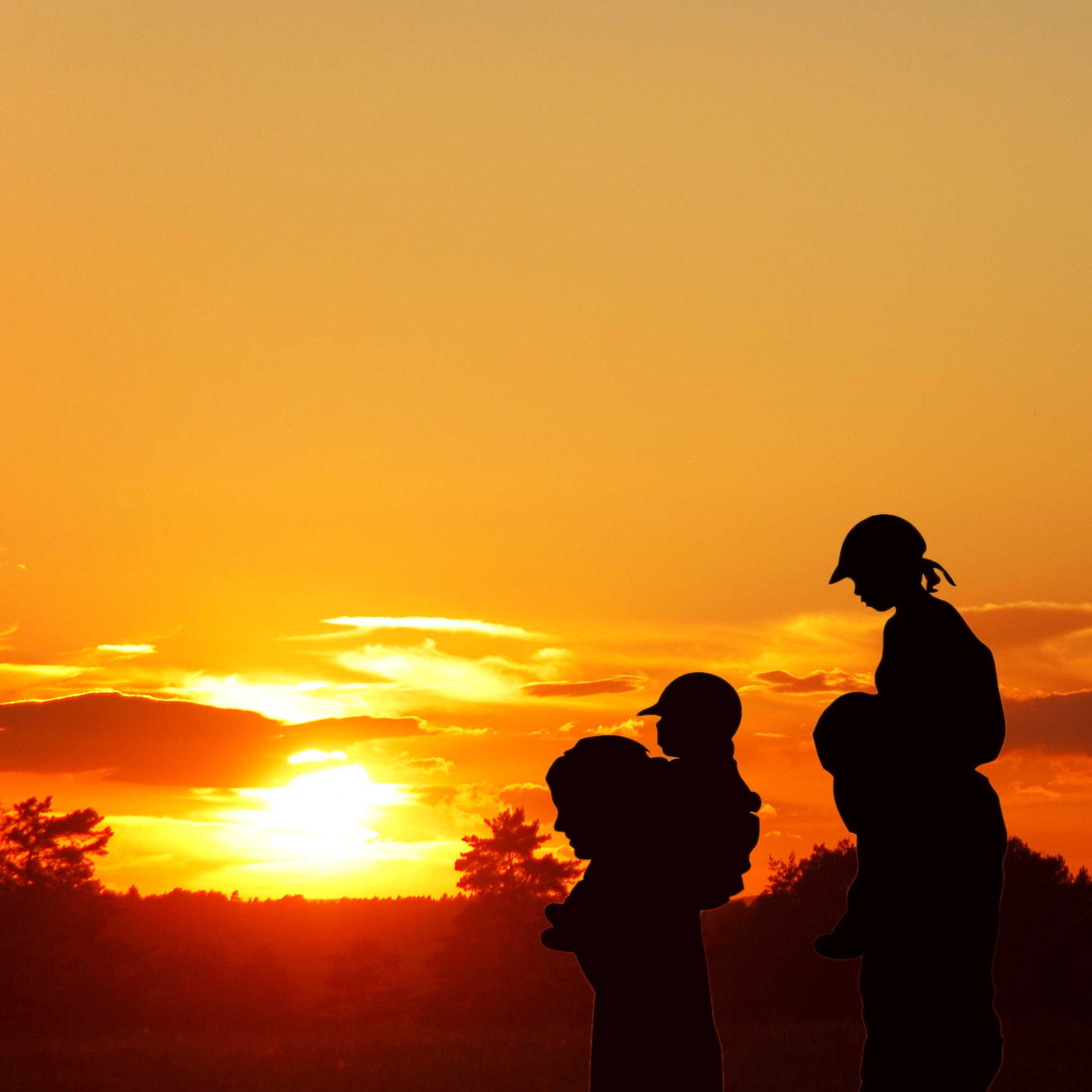 En silhuett av en mann og et barn med en solnedgang i bakgrunnen