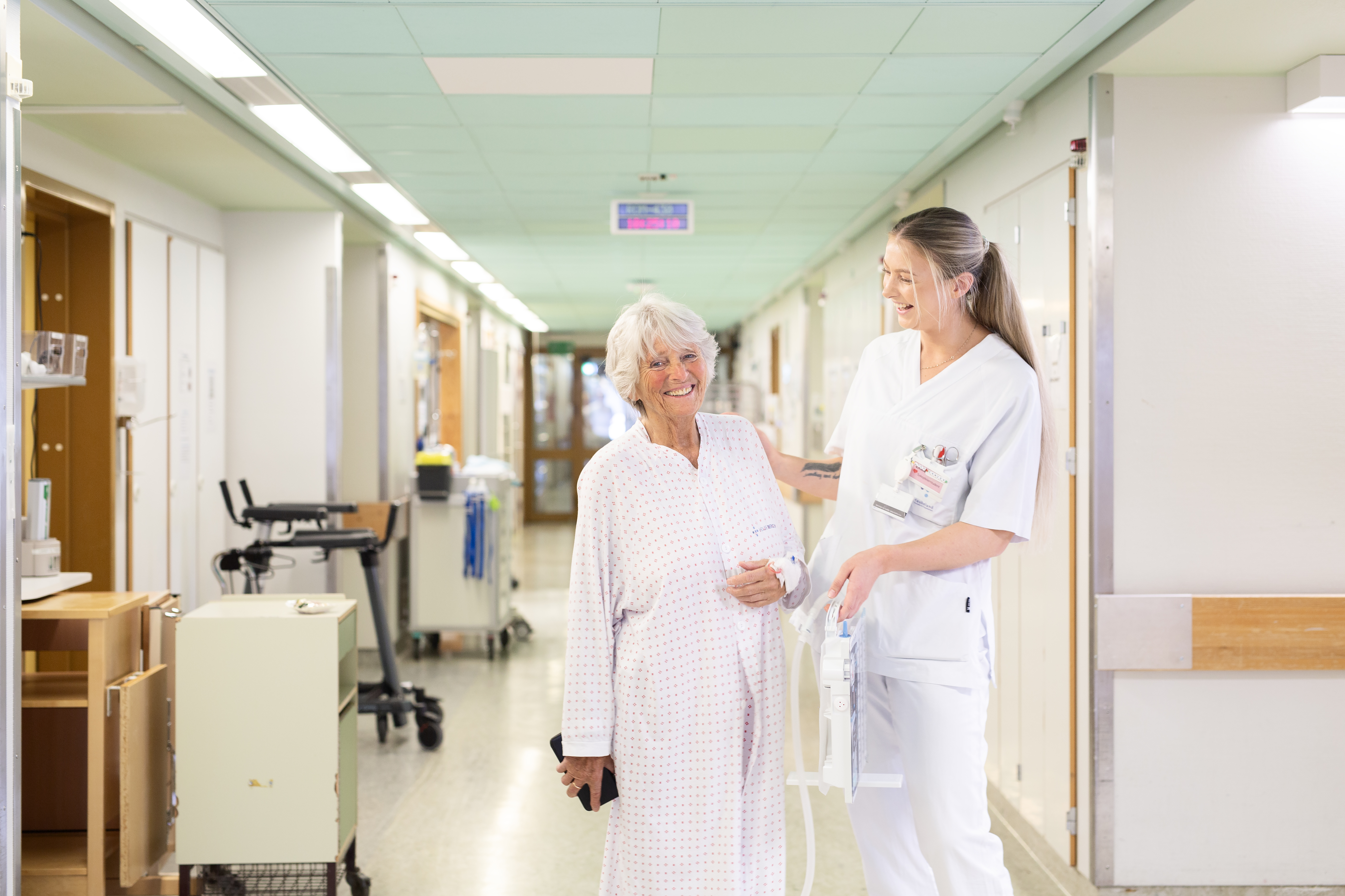 Sjukepleiar og pasient i korridor