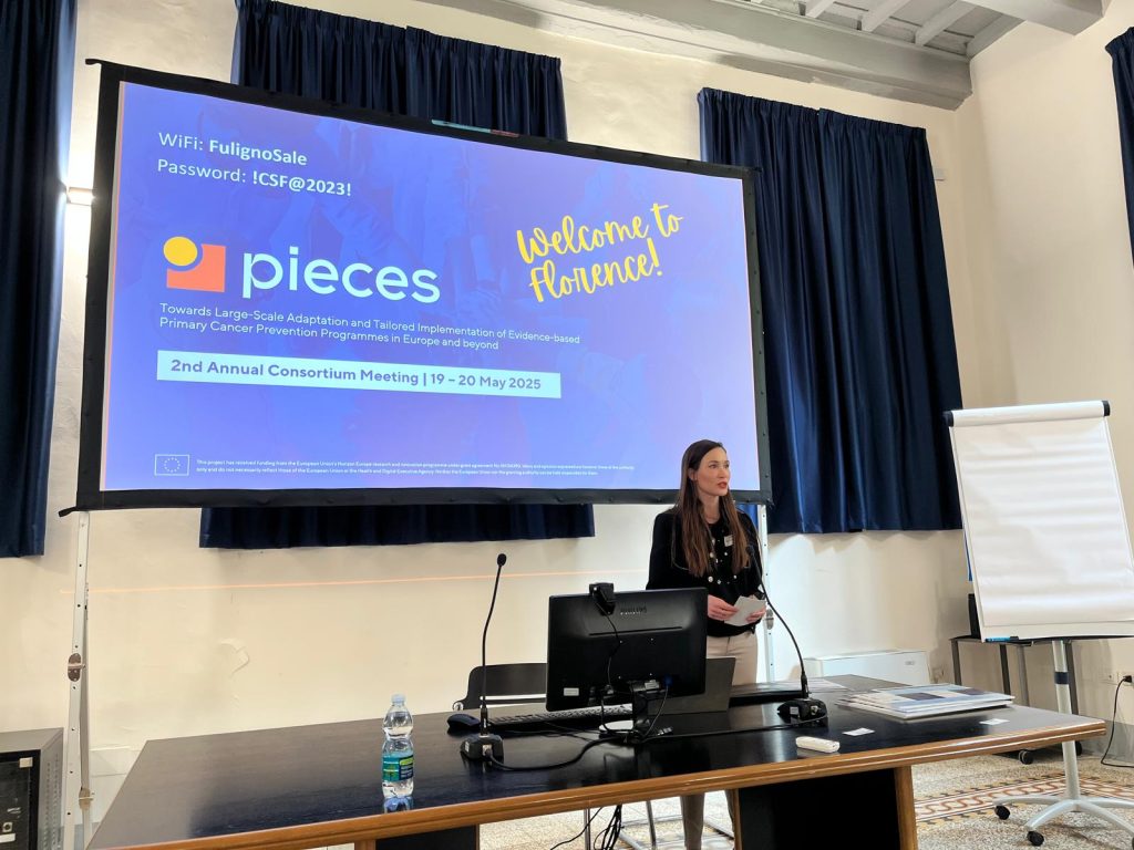 En person som står ved en talerstol foran en stor skjerm