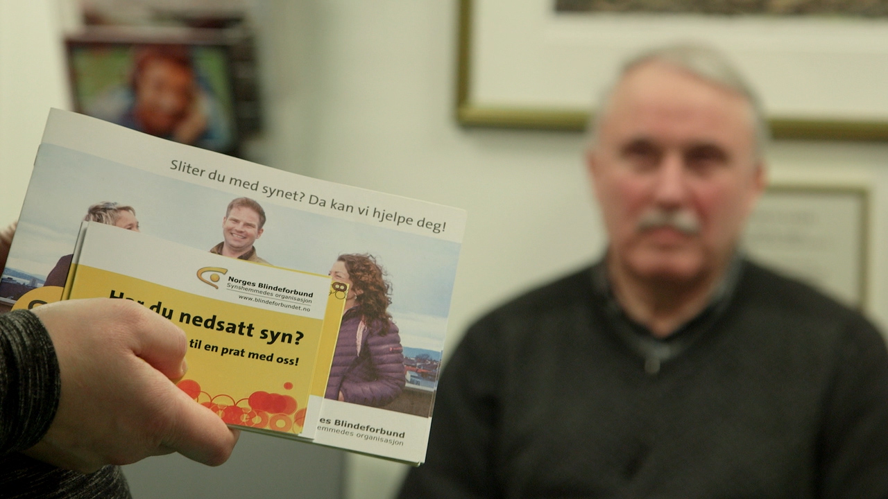 Brosjyrer fra Norges Blindeforbund vises frem til en person