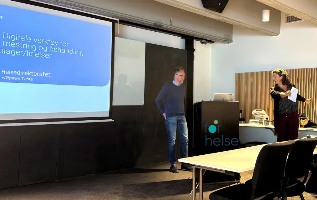 En mann og en kvinne som står foran en projektorskjerm