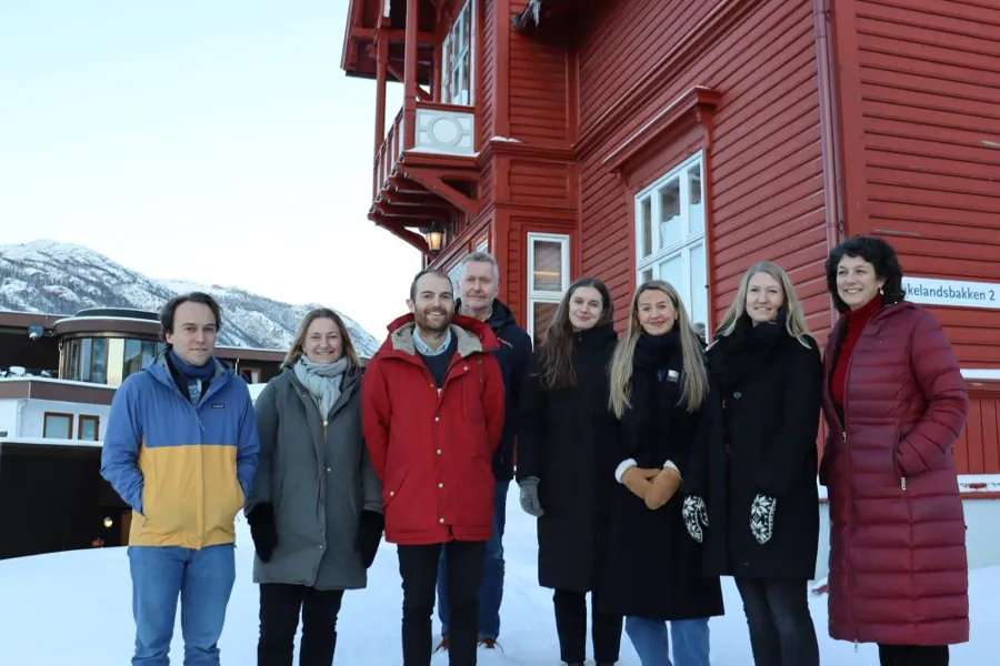 En gruppe mennesker poserer for et bilde foran en rød bygning