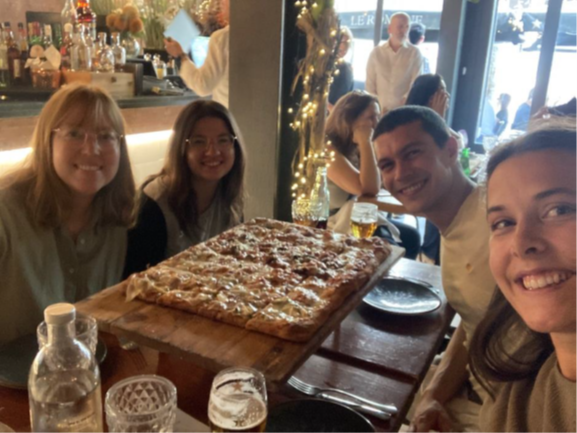 En gruppe mennesker som sitter ved et bord med en pizza