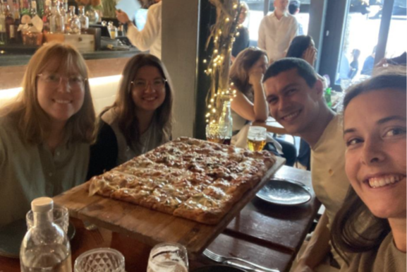 En gruppe mennesker som sitter ved et bord med en pizza