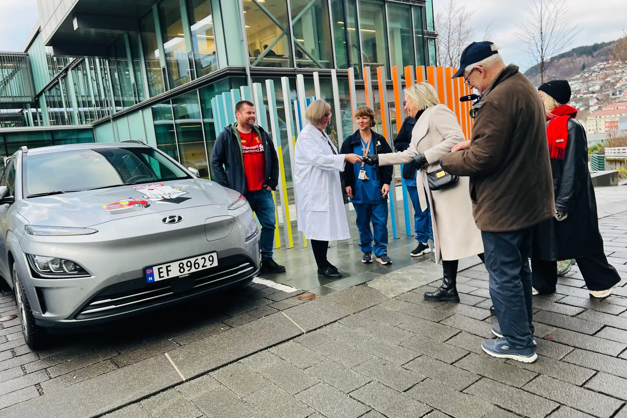 En gruppe mennesker som står ved siden av en bil